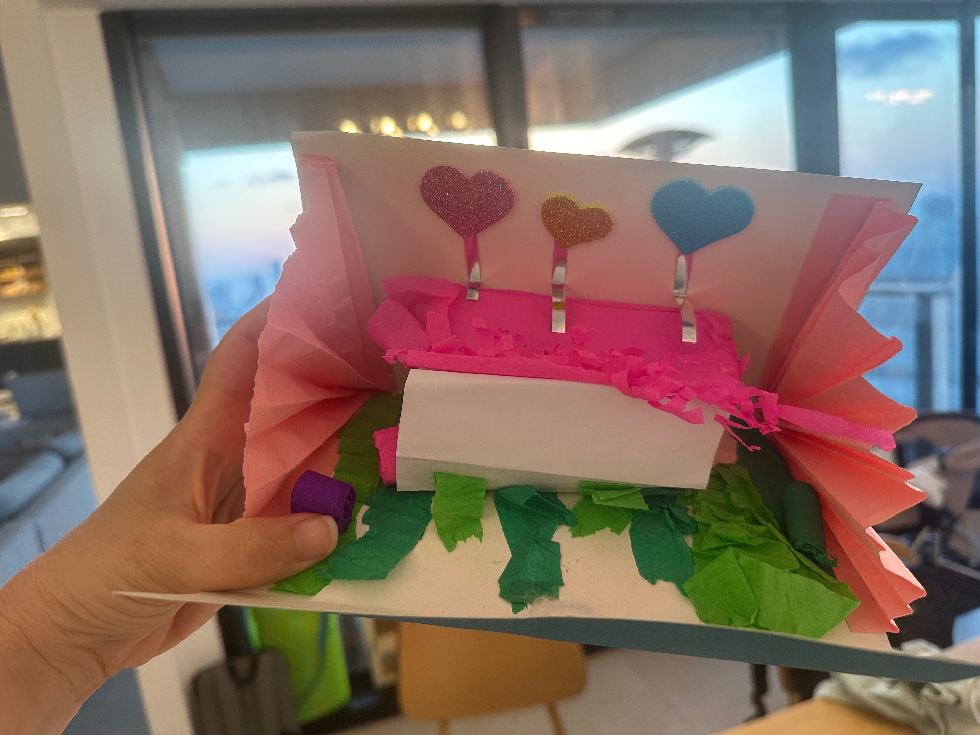 The finished card, open: fringed crepe flowers, folded paper fans and foam heart stems