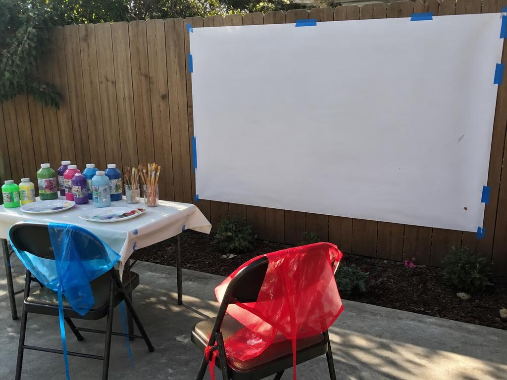 A big sheet taped to the fence, paints and aprons ready. A vertical surface changes everything.
