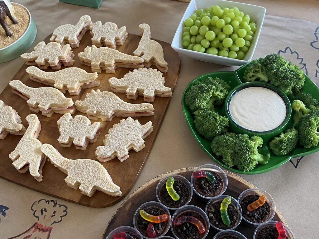 Dino sandwiches, broccoli trees, grapes and dirt cups with gummy worms.