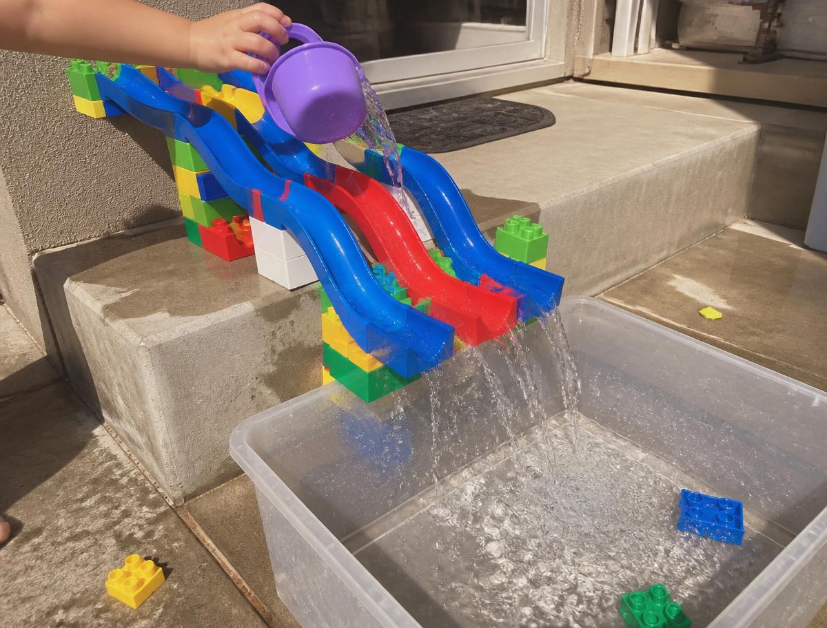 Marble-run chutes propped on brick towers, water pouring into a tub.