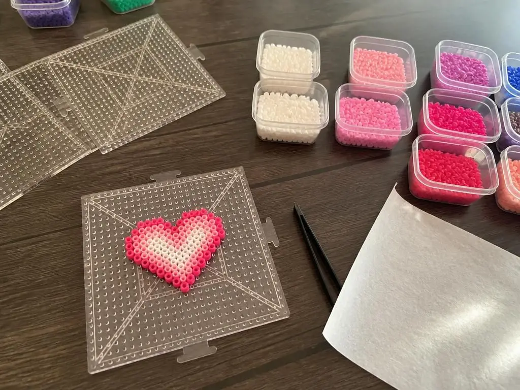 Beads sorted into tubs with the pegboard and ironing paper ready