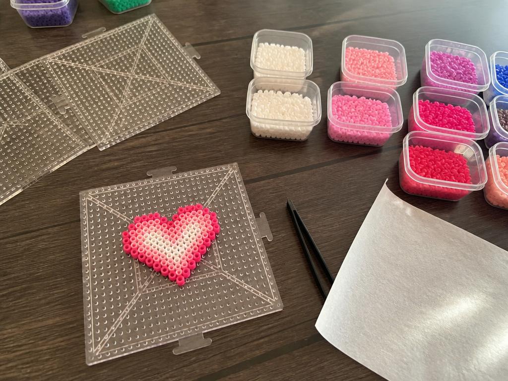 Beads sorted into tubs with the pegboard and ironing paper ready