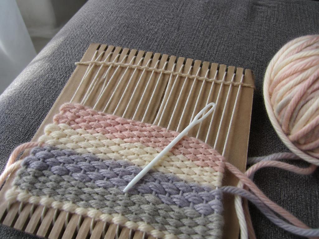 Close up of the weaving in progress, chunky yarn over white warp threads