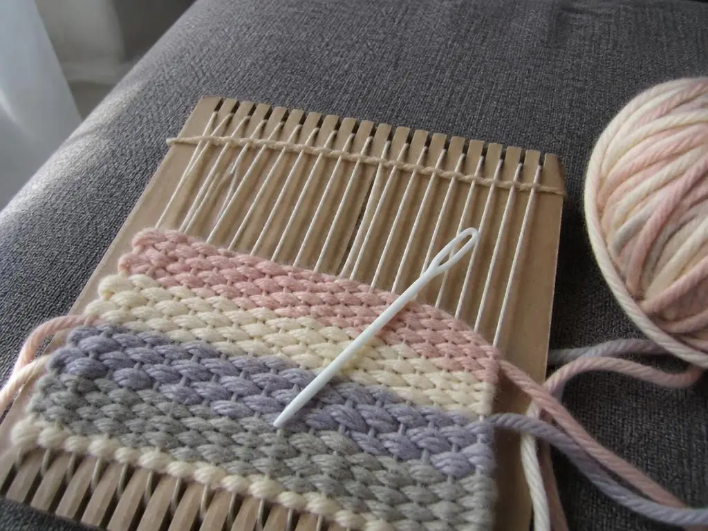 Close up of the weaving in progress, chunky yarn over white warp threads