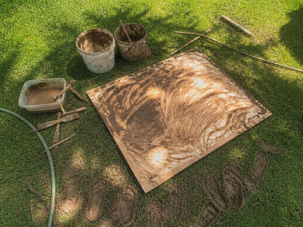 The whole setup on the grass: buckets, sticks, brushes and one muddy canvas