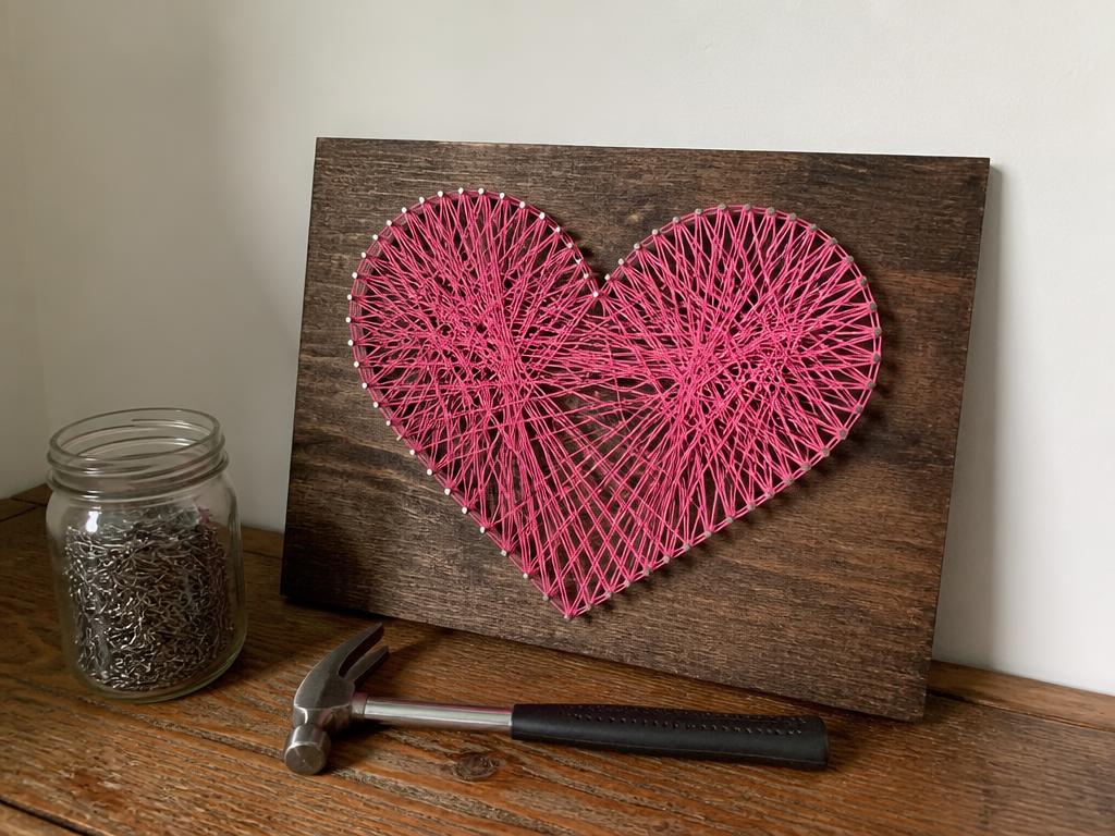 The finished heart board propped up, hammer and nails put away