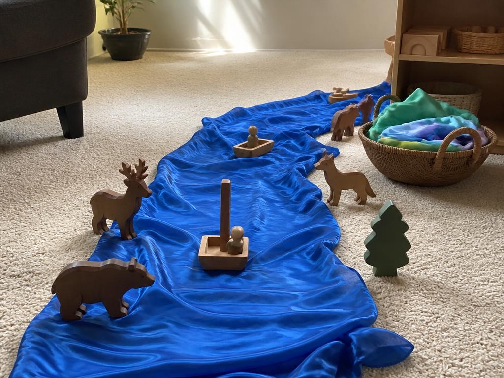 The blue silk as a river with wooden animals along the banks.