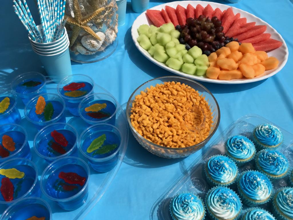 Jelly cups with gummy fish, a fruit platter and wave-frosted cupcakes.